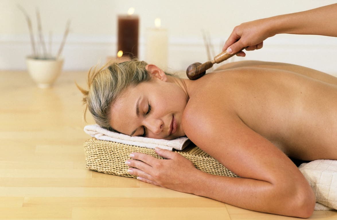 A woman is getting her back touched by a massage brush.